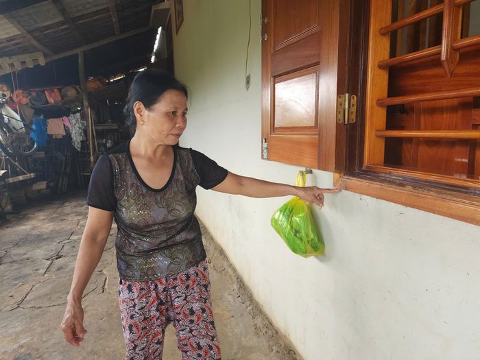 Bà Tính (vợ ông Duy) chỉ tay lên vệt nước lũ tràn vào nhà.